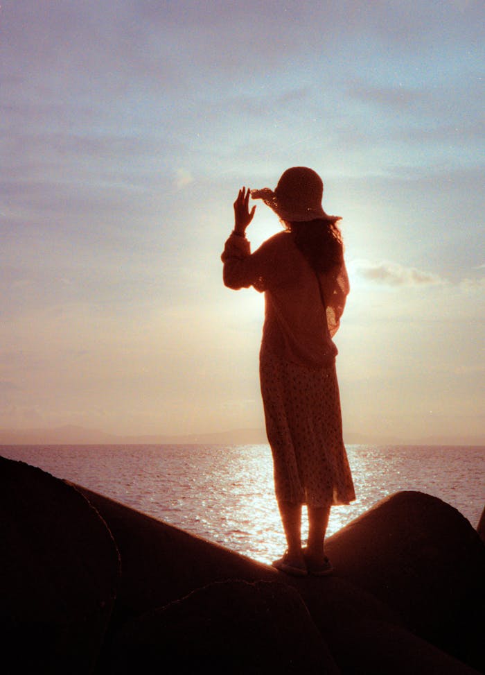 A woman in silhouette enjoying the sunrise over the sea in Quảng Ninh, Vietnam.